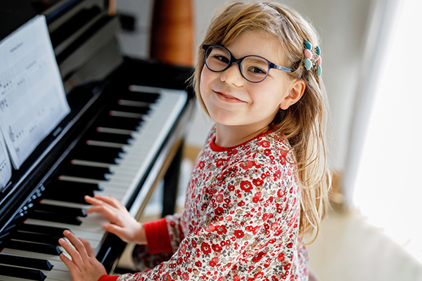 A smiling young girl is playing piano lessons at her home